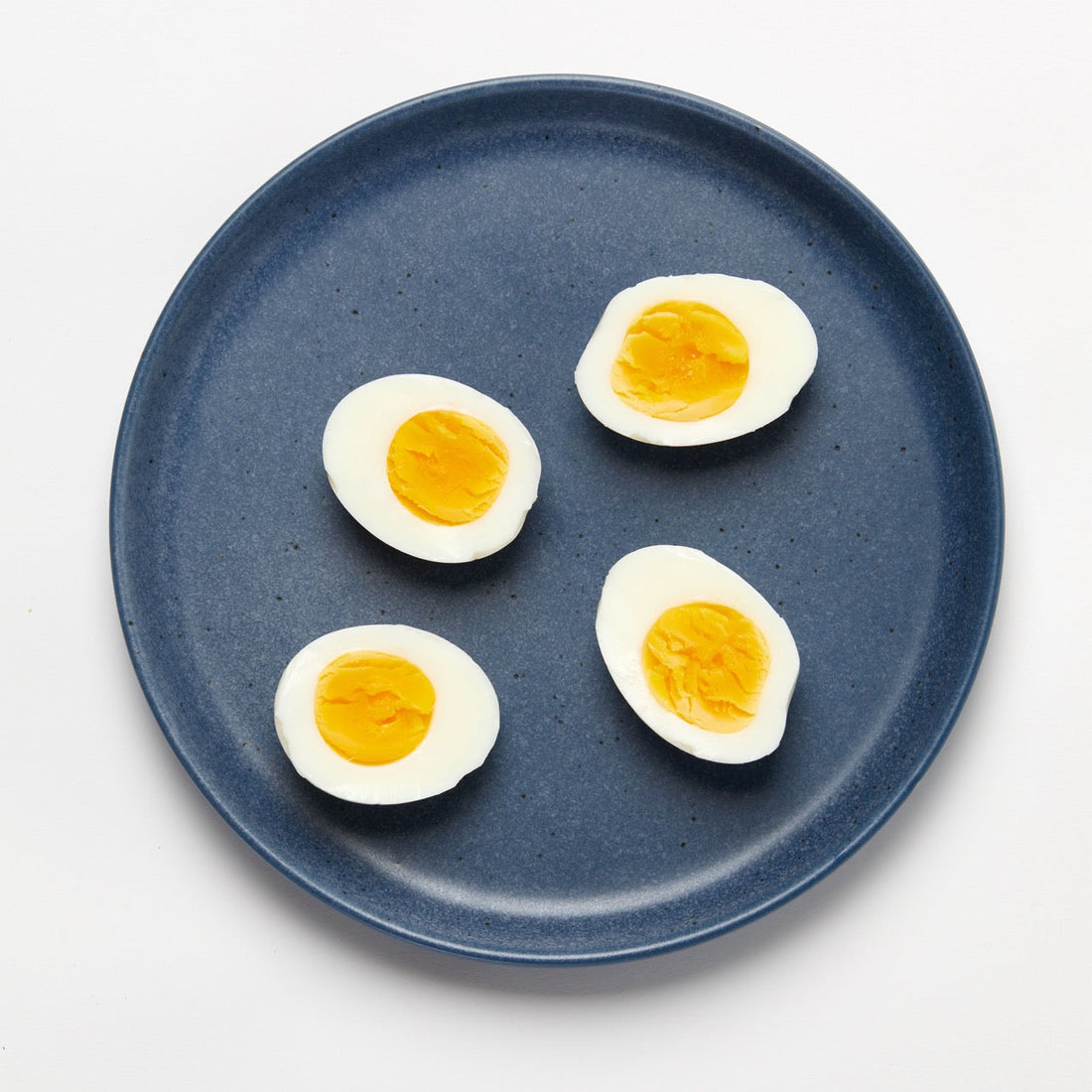 Hard boiled eggs cut in half on a blue plate