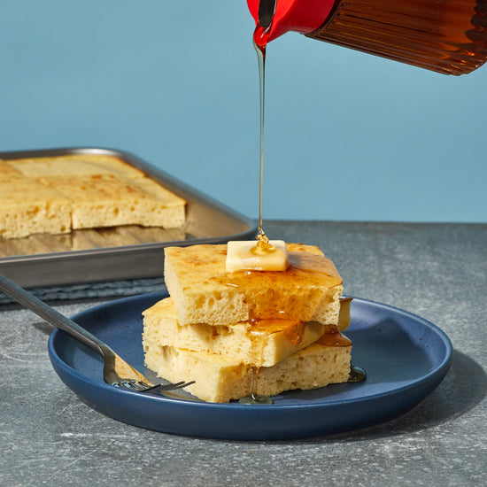 stapel vierkante pannenkoeken op een blauw bord met een drupje stroop erop